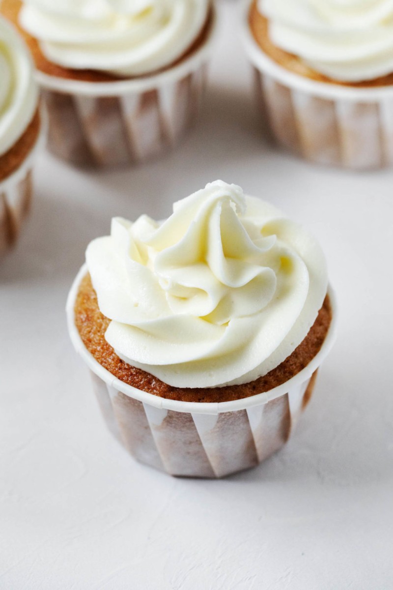 An angled photograph of apple cider cupcakes, each piped with a big swirl of dairy free frosting.