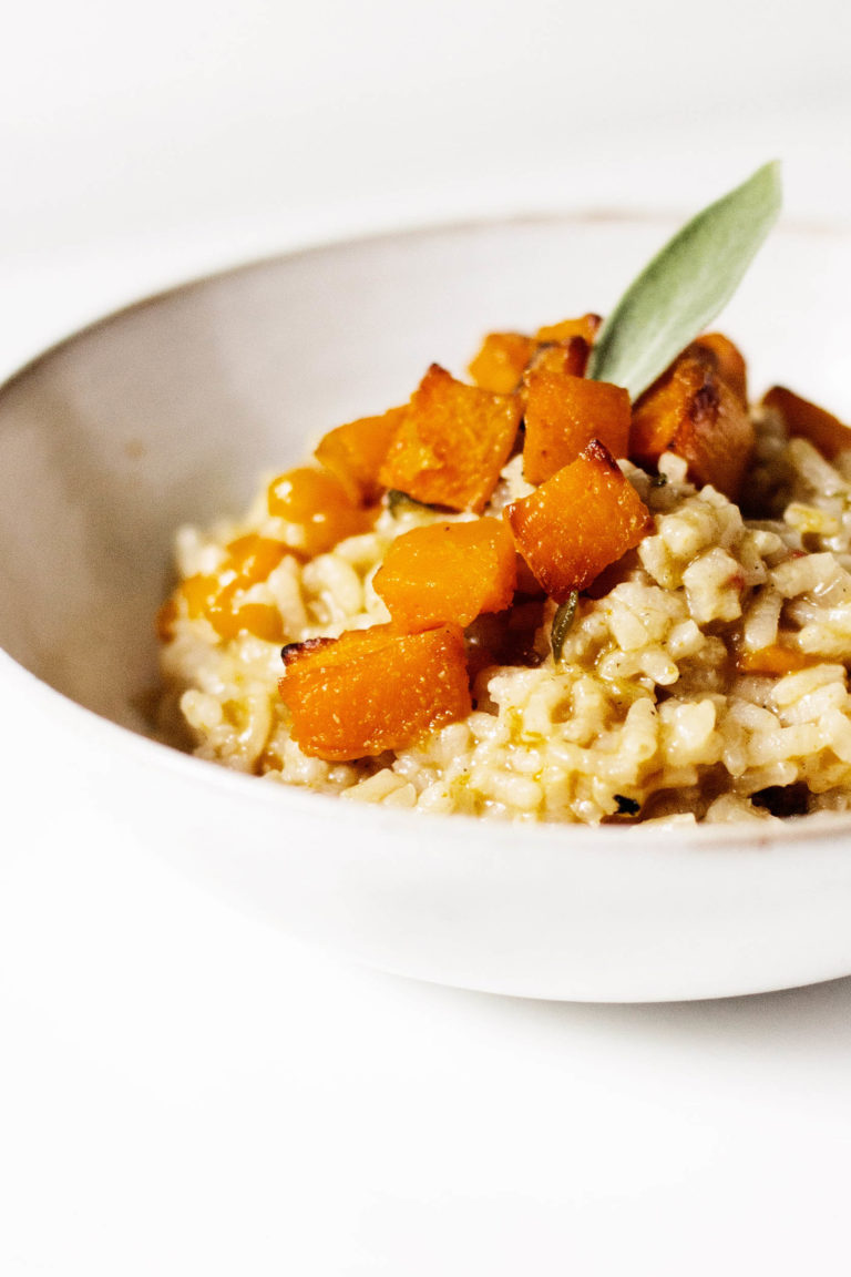 An angled shot of a vegan butternut squash risotto, garnished with sage.