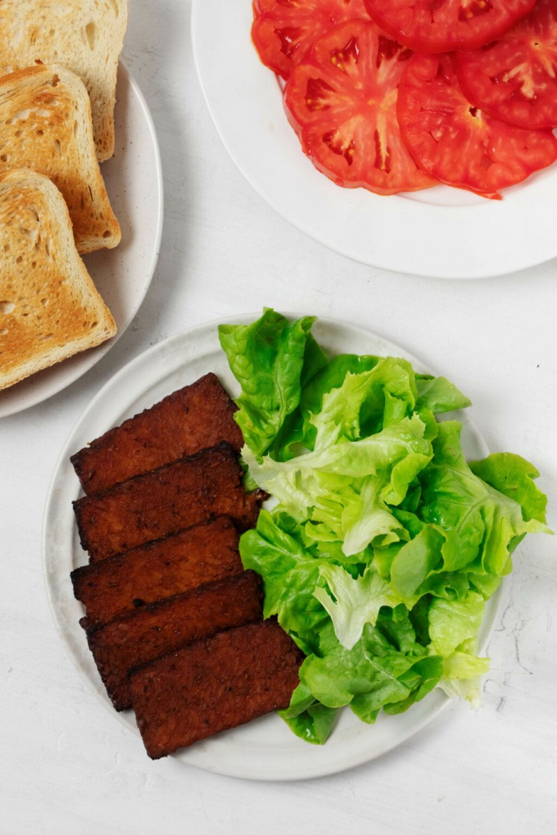 Fixings for a sandwich have been arranged on small, round white plates.