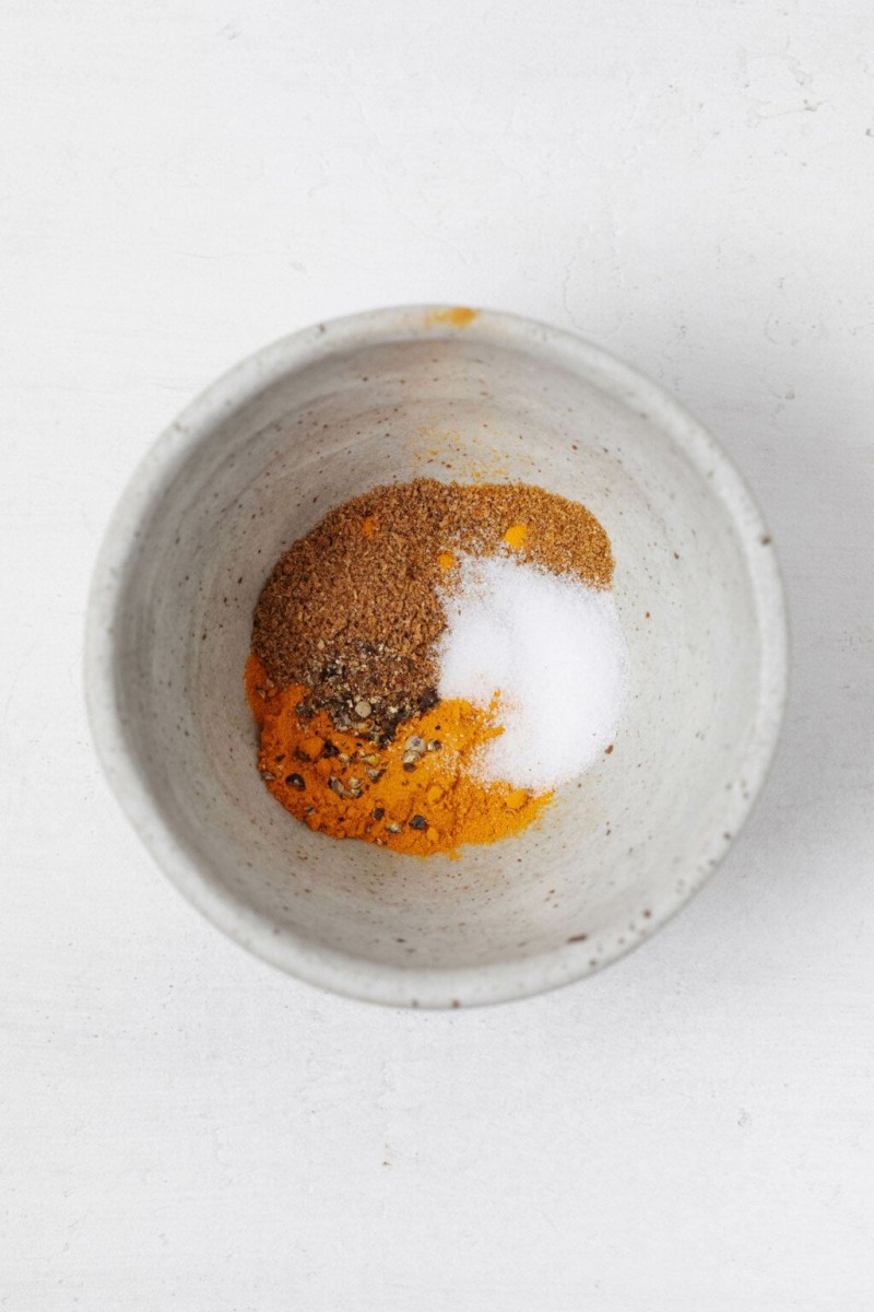 A small, ceramic bowl holds a golden-hued mixture of spices.