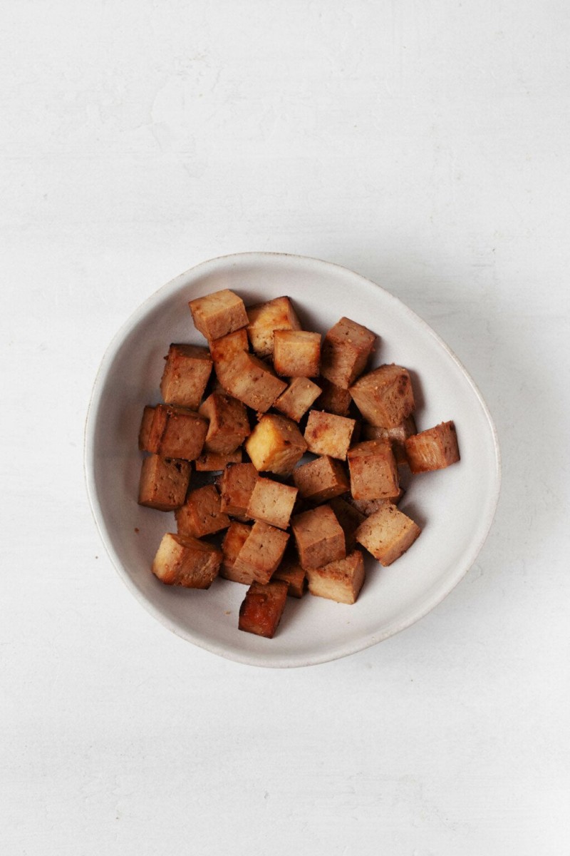 A white bowl holds baked and marinated bean curd.