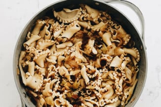 A caramelized cabbage & onion dish has just been prepared in a large, gray skillet.