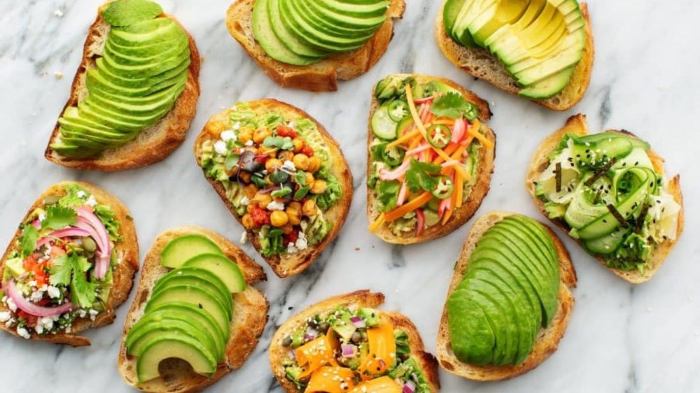 Several slices of avocado toast topped with delicious ingredients.