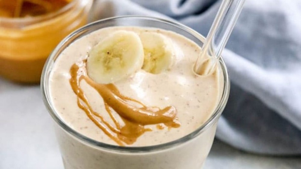 A glass cup filled with a cool peanut butter smoothie