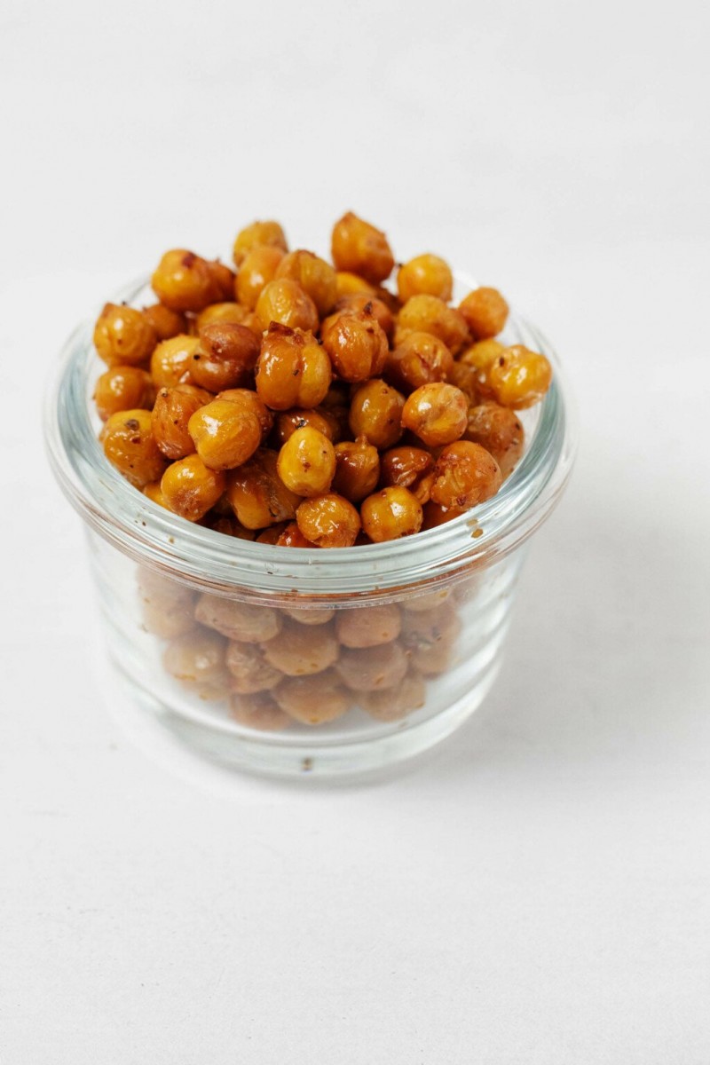 An angled, mostly overhead image of beans that have become crispy in the oven. They're overflowing in a small, glass mason jar.