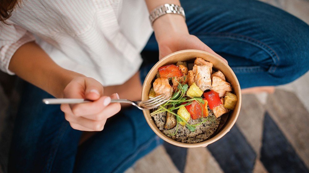 Woman sitting down and eating a healthy meal.