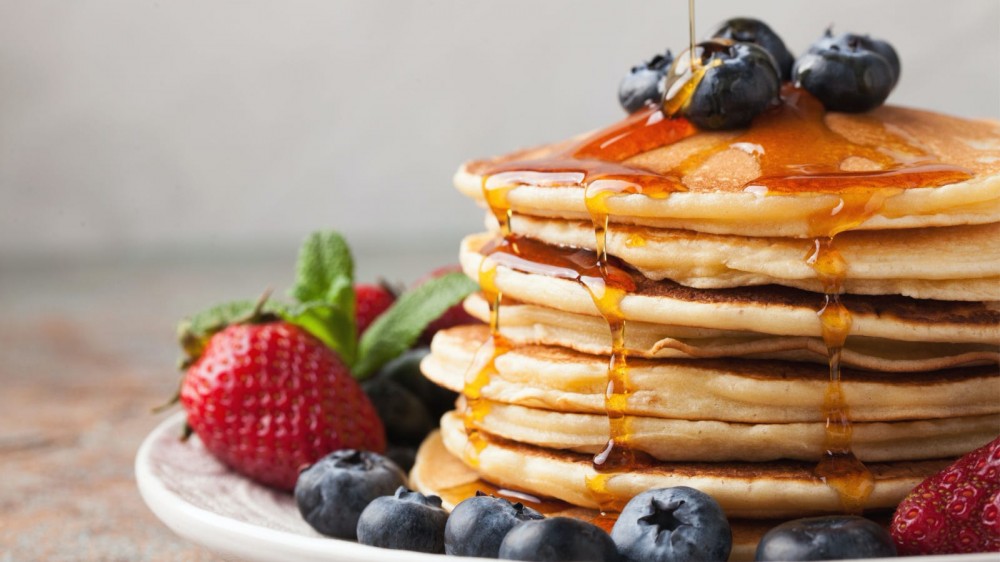 Stack of pancakes with berries and maple syrup