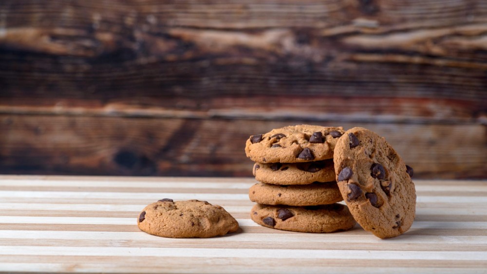 A stack of chocolate chip cookies sit on a table.