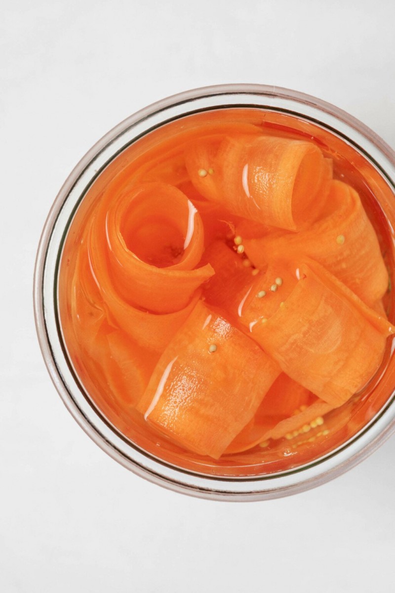 An overhead image of a jar filled with pickled carrot ribbons.