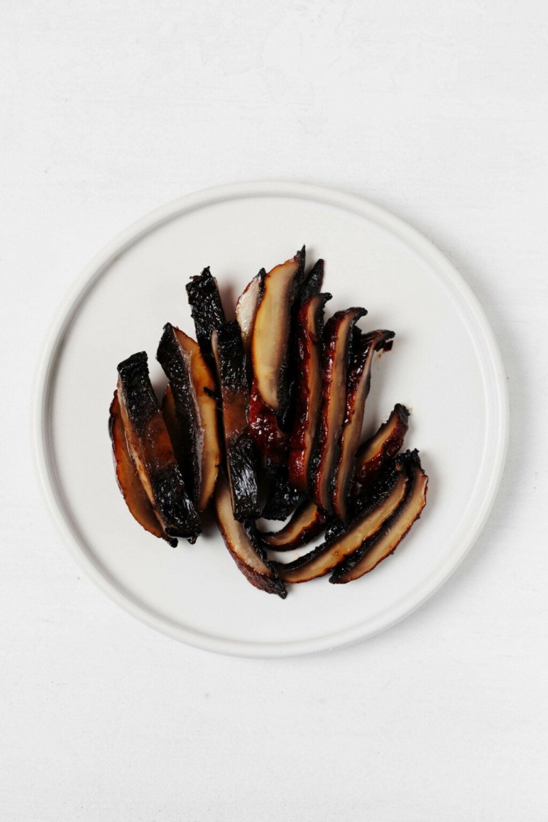 A white plate holds a few sliced pieces of roasted portobello mushroom.